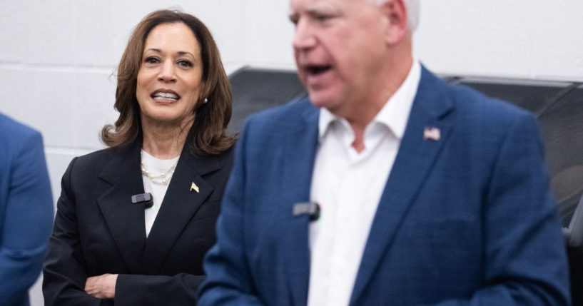 Democratic presidential candidate US Vice President Kamala Harris listen to her running mate, Governor Tim Walz, speak during a visit with members of the marching band at Liberty County High School in Hinesville, Georgia, August 28, 2024, as they travel across Georgia for a 2-day campaign bus tour.