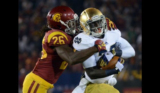 Cierre Wood #20 of the Notre Dame Fighting Irish protects the ball as he is tackled by Josh Shaw #26 of the USC Trojans during a 22-13 Notre Dame win at Los Angeles Memorial Coliseum on November 24, 2012 in Los Angeles, California.