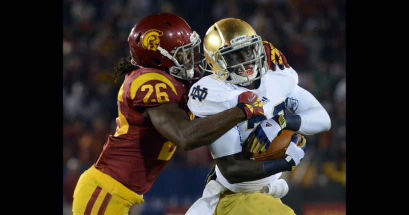 Cierre Wood #20 of the Notre Dame Fighting Irish protects the ball as he is tackled by Josh Shaw #26 of the USC Trojans during a 22-13 Notre Dame win at Los Angeles Memorial Coliseum on November 24, 2012 in Los Angeles, California.