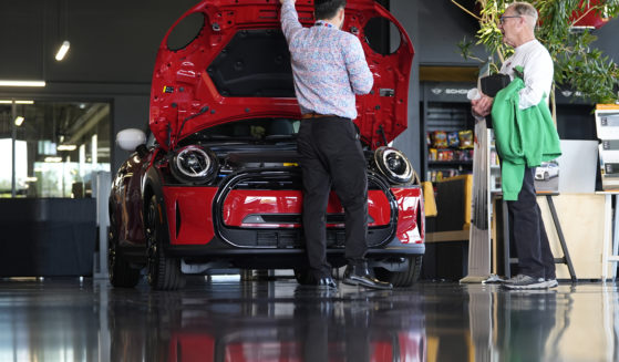 A salesperson shows an unsold 2024 Cooper SE electric hardtop to a prospective buyer in the showroom of a Mini dealership Wednesday, May 1, 2024, in Highlands Ranch, Colorado.