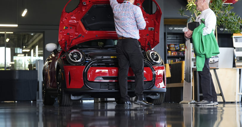 A salesperson shows an unsold 2024 Cooper SE electric hardtop to a prospective buyer in the showroom of a Mini dealership Wednesday, May 1, 2024, in Highlands Ranch, Colorado.