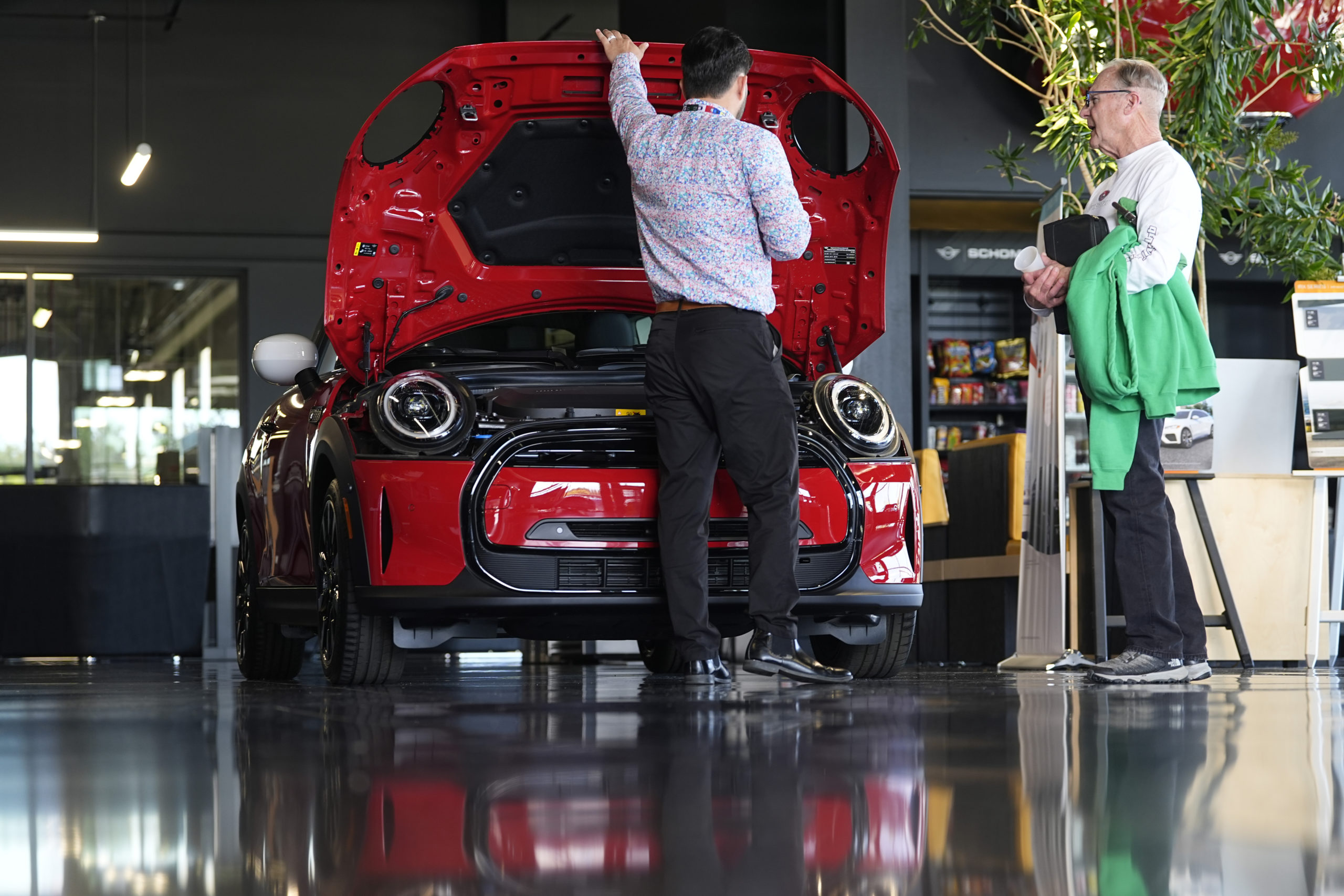 A salesperson shows an unsold 2024 Cooper SE electric hardtop to a prospective buyer in the showroom of a Mini dealership Wednesday, May 1, 2024, in Highlands Ranch, Colorado.