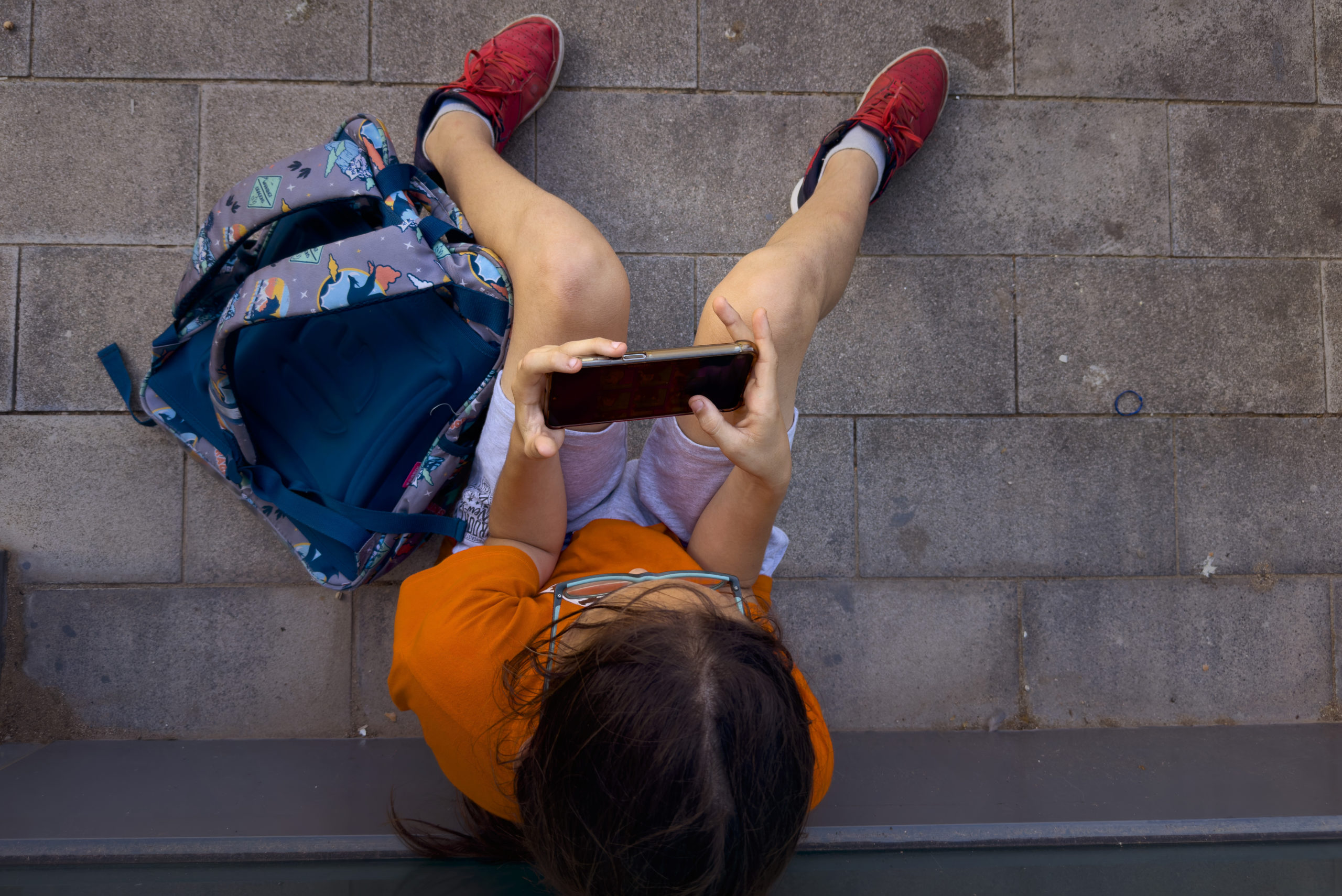 An 11-year-old boy plays with his father's phone outside school in Barcelona, Spain, Monday, June 17, 2024.