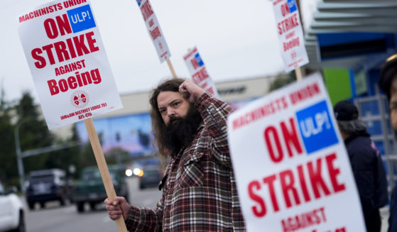 Jacob Bustad, a machinist who has worked for Boeing for 14 years, holds up a fist to passing drivers as union members work the picket line after voting to reject a contract offer and go on strike on Sunday near the company's factory in Everett, Washington.