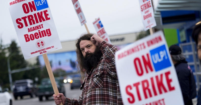 Jacob Bustad, a machinist who has worked for Boeing for 14 years, holds up a fist to passing drivers as union members work the picket line after voting to reject a contract offer and go on strike on Sunday near the company's factory in Everett, Washington.