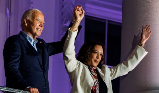 President Joe Biden, left, and Vice President Kamala Harris, right, join hands in the air after watching the fireworks on the National Mall from the White House balcony in Washington, D.C., on July 4.