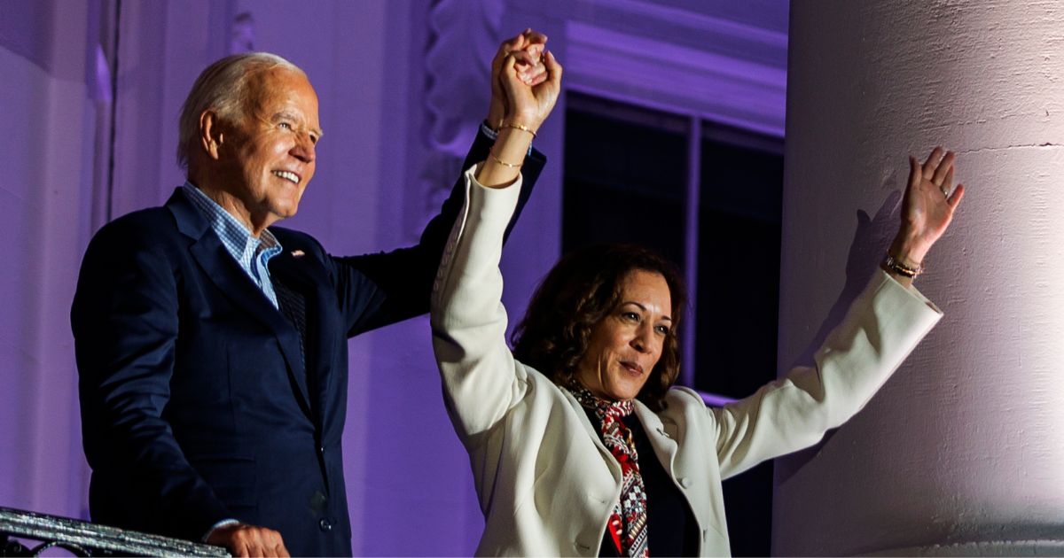 President Joe Biden, left, and Vice President Kamala Harris, right, join hands in the air after watching the fireworks on the National Mall from the White House balcony in Washington, D.C., on July 4.