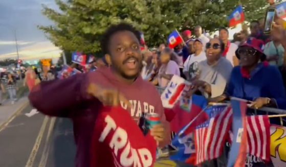 A black Trump supporter confronts Haitian protesters outside the former president's New York rally Wednesday.