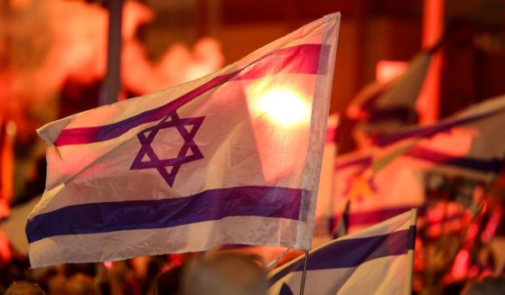 Demonstrators light flares and wave national flags during an anti-government protest calling for action to secure the release of Israeli hostages held captive since the October 7 attacks by Palestinian militants.