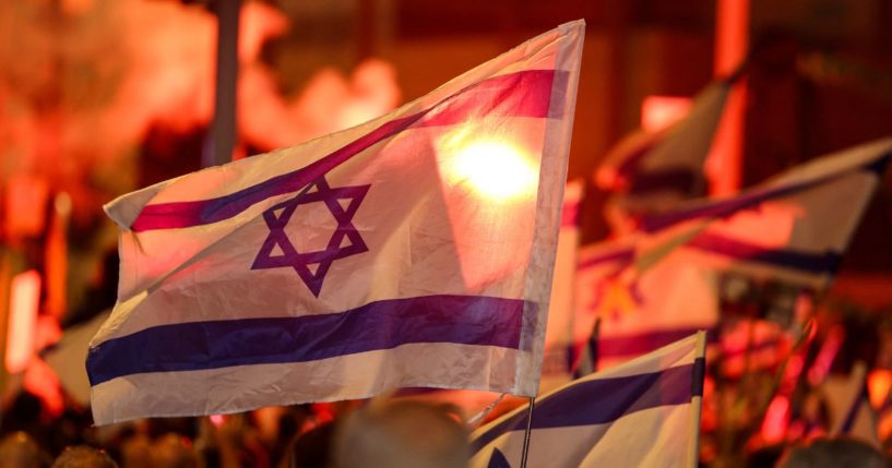 Demonstrators light flares and wave national flags during an anti-government protest calling for action to secure the release of Israeli hostages held captive since the October 7 attacks by Palestinian militants.