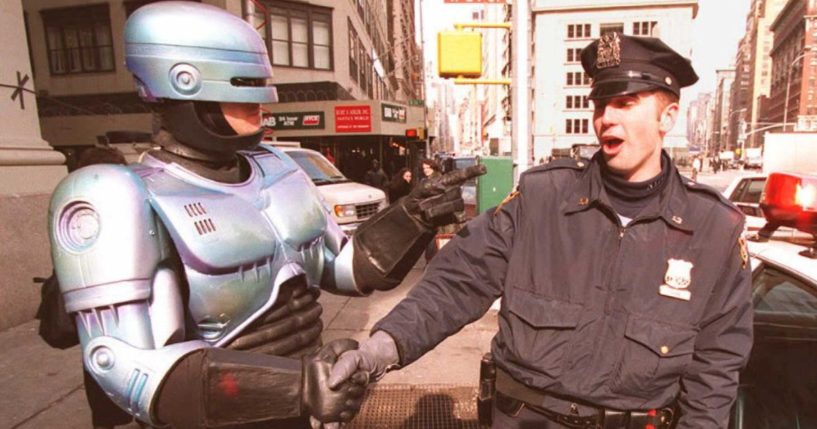 New York City Police Officer Paul Dean, right, gets a handshake from a person dressed as 