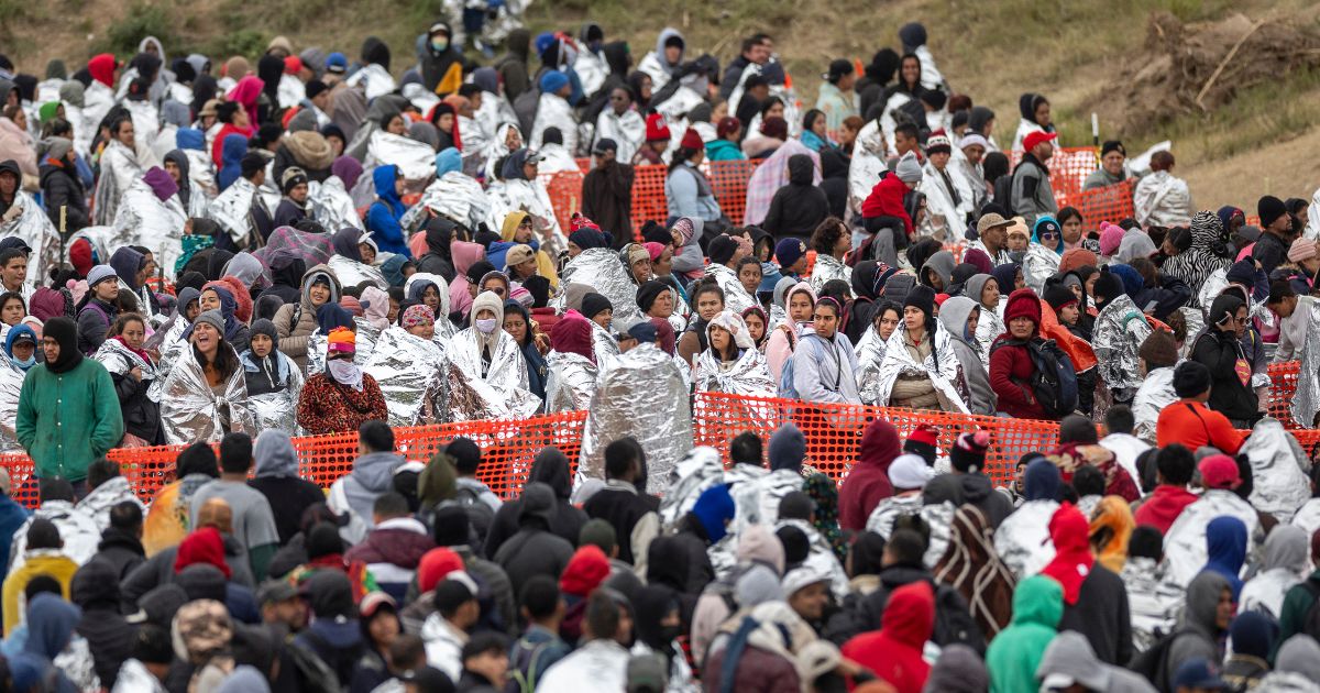 Immigrants wait to be processed at a U.S. Border Patrol transit center after they crossed the border from Mexico on December 20, 2023 in Eagle Pass, Texas. A late-year surge of migrants crossing the U.S.southern border has overwhelmed U.S. immigration officials.