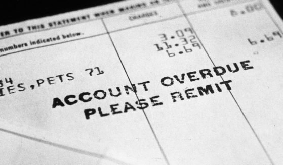 circa 1965: Close-up of an overdue bill, sitting in front of a black backdrop. It reads 'Account Overdue- Please Remit.'