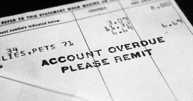 circa 1965: Close-up of an overdue bill, sitting in front of a black backdrop. It reads 'Account Overdue- Please Remit.'