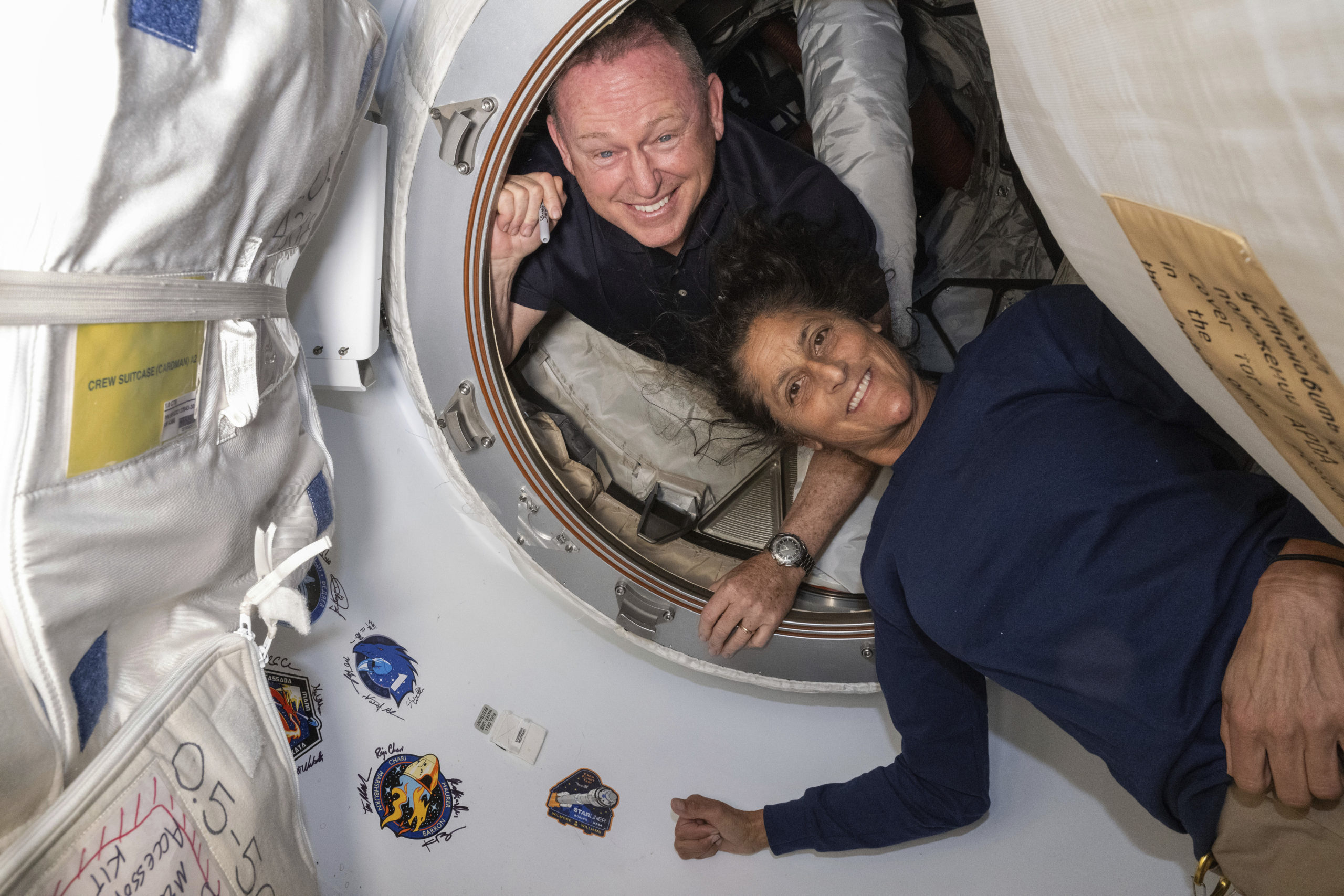 Boeing Crew Flight Test astronauts Butch Wilmore, left, and Suni Williams pose for a June 13 portrait inside the vestibule between the forward port on the International Space Station's Harmony module and Boeing's Starliner spacecraft.