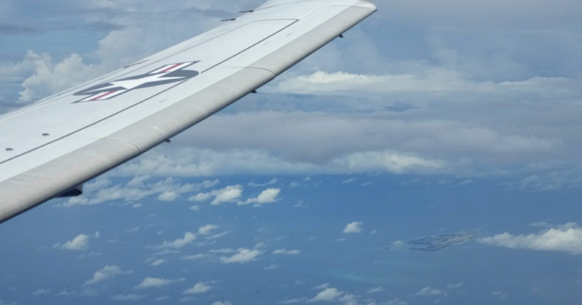 A U.S. P-8A Poseidon reconnaissance plane flies near Chinese structures and buildings on the man-made Fiery Cross Reef at the Spratlys group of islands in the South China Sea are seen on March 20, 2022.