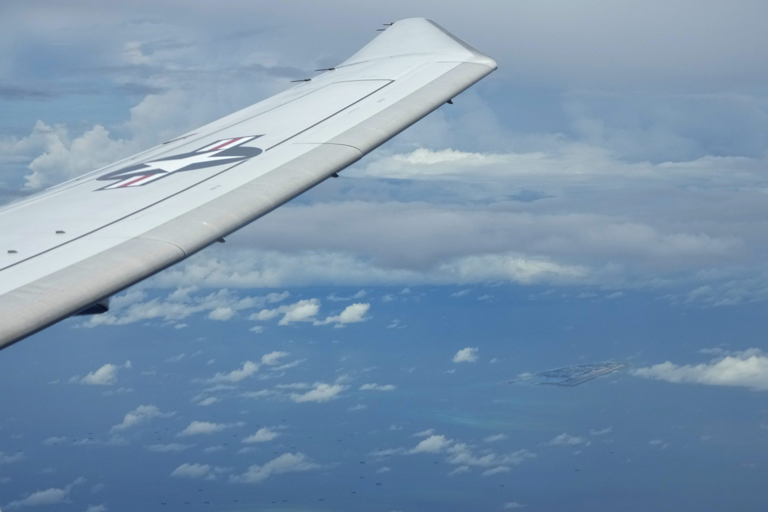 A U.S. P-8A Poseidon reconnaissance plane flies near Chinese structures and buildings on the man-made Fiery Cross Reef at the Spratlys group of islands in the South China Sea are seen on March 20, 2022.