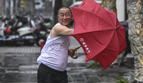 In this photo released by Xinhua News Agency, a man holding an umbrella struggles against the wind following the landfall of typhoon Yagi in Haikou, south China's Hainan Province on Friday.