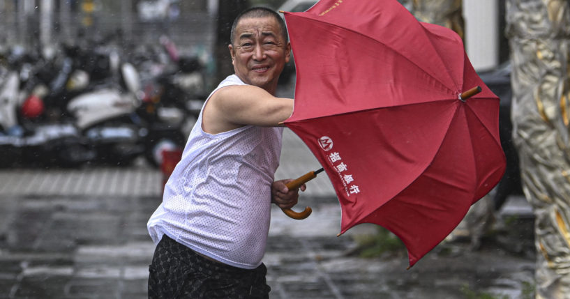 In this photo released by Xinhua News Agency, a man holding an umbrella struggles against the wind following the landfall of typhoon Yagi in Haikou, south China's Hainan Province on Friday.