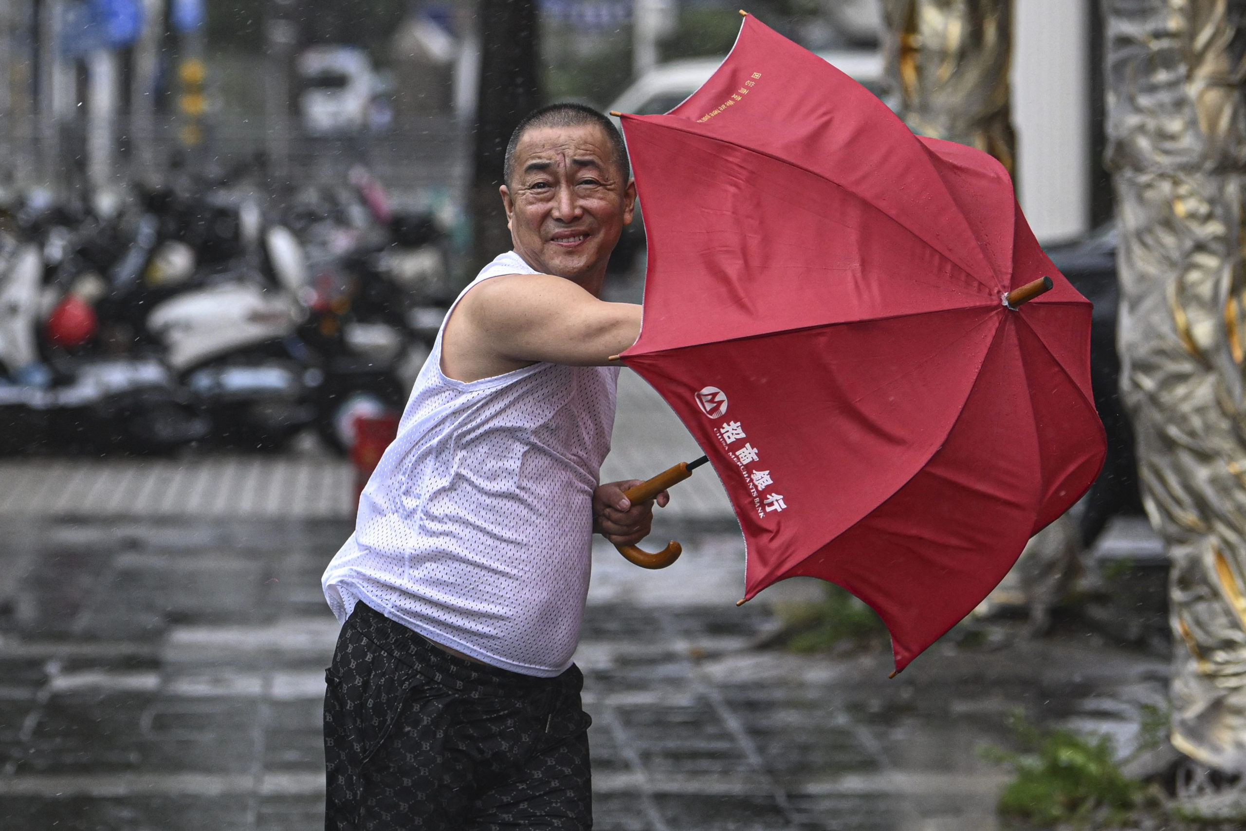 In this photo released by Xinhua News Agency, a man holding an umbrella struggles against the wind following the landfall of typhoon Yagi in Haikou, south China's Hainan Province on Friday.