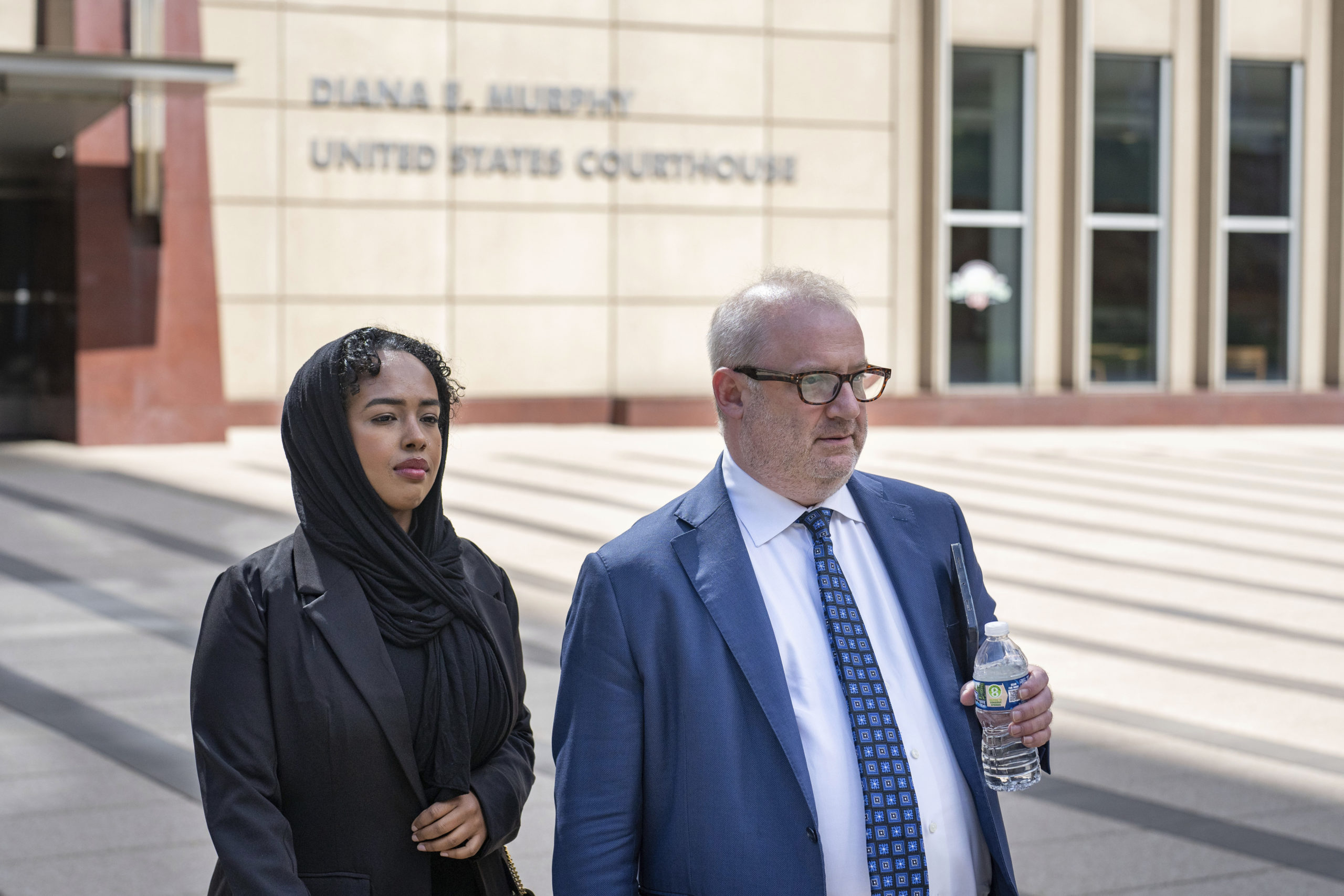 Ladan Mohamed Ali, left, a Seattle woman who attempted to bribe a Minnesota juror with a bag of $120,000 in cash in exchange for an acquittal in one of the country's largest COVID-19-related fraud cases, and her attorney, Eric Newmark, leave the Diana E. Murphy U.S. Courthouse on Thursday in Minneapolis, following after a hearing where she plead guilty.