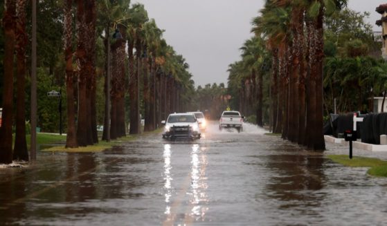 Vehicles drive along a flooded street as Hurricane Helene churns offshore on September 26, 2024 in St. Pete Beach, Florida.