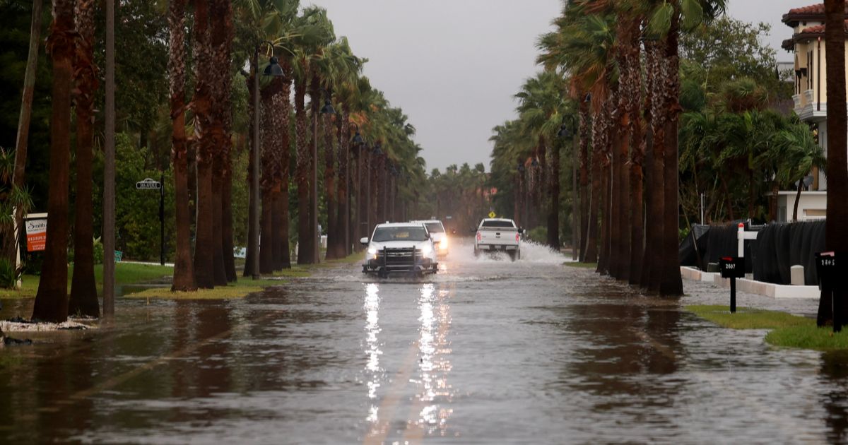 Vehicles drive along a flooded street as Hurricane Helene churns offshore on September 26, 2024 in St. Pete Beach, Florida.