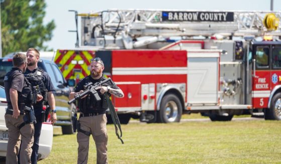 Officers hold guns while talking outside after a shooting at Apalachee High School on September 4, 2024 in Winder, Georgia.