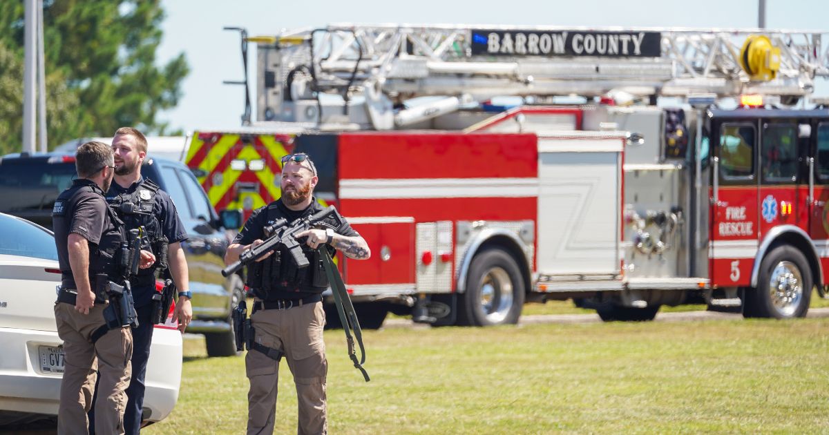 Officers hold guns while talking outside after a shooting at Apalachee High School on September 4, 2024 in Winder, Georgia.