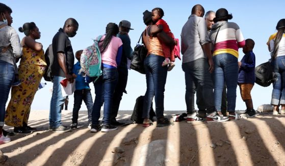 Immigrants from Haiti, who crossed through a gap in the U.S.-Mexico border barrier, wait in line to be processed by the U.S. Border Patrol on May 20, 2022 in Yuma, Arizona.