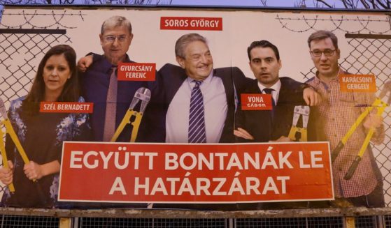 A Fidesz-party sponsored poster featuring a montage of billionaire investor George Soros (C) posing with (L to R) Politics Can Be Different (Lehet Mas a Politika, or LMP) party candidate Bernadett Szel, former Hungarian prime minister and Democratic Coalition (Hungarian: Demokratikus Koalicio, or DK) party candidate Ferenc Gyurcsany, Jobbik party candidate Gabor Vona, and Dialogue for Hungary (Parbeszed Magyarorszagert) party candidate Gergely Karacsony, all holding bolt cutters after having cut the border fence behind them, hangs prior to the upcoming Hungarian parliamentary elections on April 8, on March 20, 2018 in Budapest, Hungary.