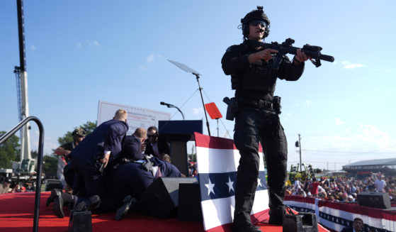 An armed law enforcement officer mans the stage durign the aftermath of the assassination attempt on former President Donald Trump on July 13 in Butler, Pennsylvania.