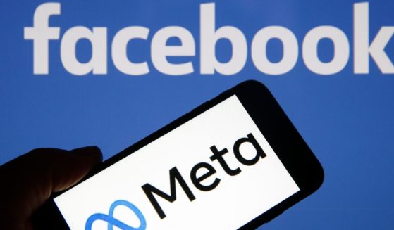 The Meta logo is displayed on the screen of an iPhone in front of a Facebook logo in Paris, France, on Oct. 29, 2021.