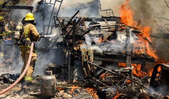 Firefighters knock down a structure fire that ignited from a burning generator and briefly spread to a small spot fire at a home during the Thompson fire in Oroville, California, on July 3.