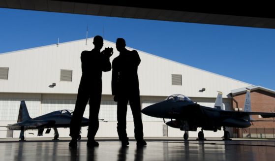 Pilots with the US Air Force stand inside a hangar alongside a F-15 fighter jet and a T-38 Talon trainer jet during the inaugural Trilateral Exercise between the US Air Force, United Kingdom's Royal Air Force and the French Air Force at Joint Base Langley-Eustis in Hampton, Virginia, on Dec. 15, 2015.