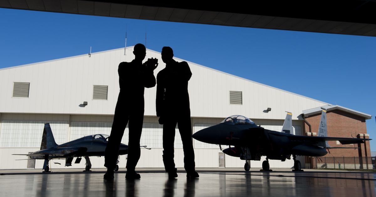 Pilots with the US Air Force stand inside a hangar alongside a F-15 fighter jet and a T-38 Talon trainer jet during the inaugural Trilateral Exercise between the US Air Force, United Kingdom's Royal Air Force and the French Air Force at Joint Base Langley-Eustis in Hampton, Virginia, on Dec. 15, 2015.