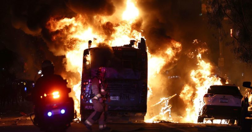 A firefighter and police officer work near a Metro bus burning following Dodger fan celebrations in the area which turned unruly, after the Los Angeles Dodgers defeated the New York Yankees in Game 5 to win the World Series in Los Angeles on Wednesday.