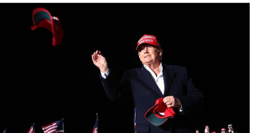 Former President Donald Trump tosses a MAGA hat to the crowd before speaking at a rally in Florence, Arizona, on Jan. 15, 2022.