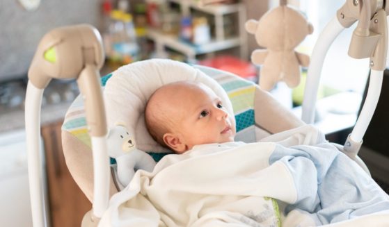 Portrait of a boy in the electric cradle in the kitchen.