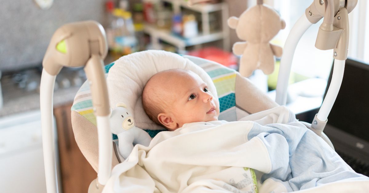 Portrait of a boy in the electric cradle in the kitchen.