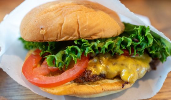 Close-up of a cheeseburger with tomato and lettuce in a paper wrapper at Shake Shack, Walnut Creek, California, August 25, 2024.