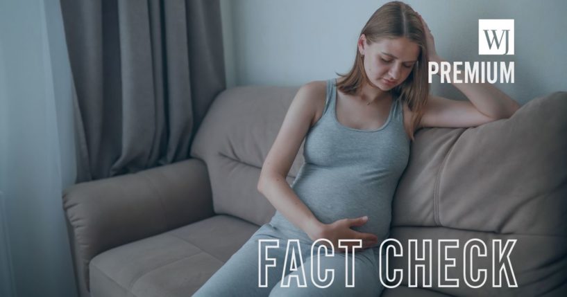 This stock image shows a young pregnant woman sitting on a sofa.