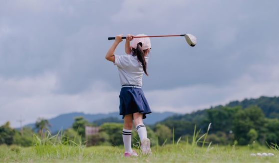 This stock image shows a young girl training to play golf.