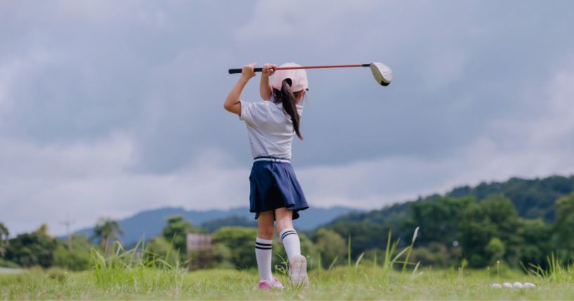 This stock image shows a young girl training to play golf.