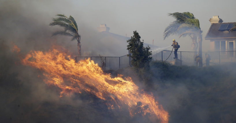 A firefighter sprays water in front of an advancing wildfire in Porter Ranch, California, on Oct. 11, 2019.