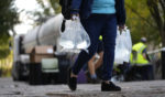 A person carries bags of fresh water after filling up from a tanker at a distribution site in the aftermath of Hurricane Helene Wednesday.