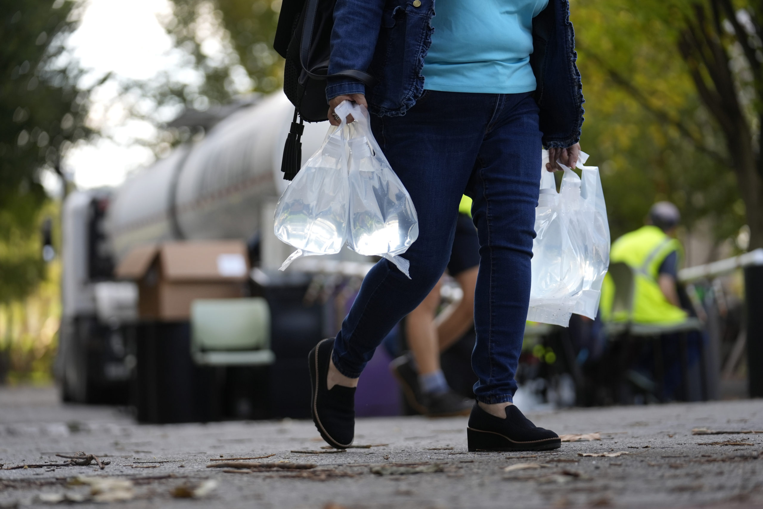 A person carries bags of fresh water after filling up from a tanker at a distribution site in the aftermath of Hurricane Helene Wednesday.