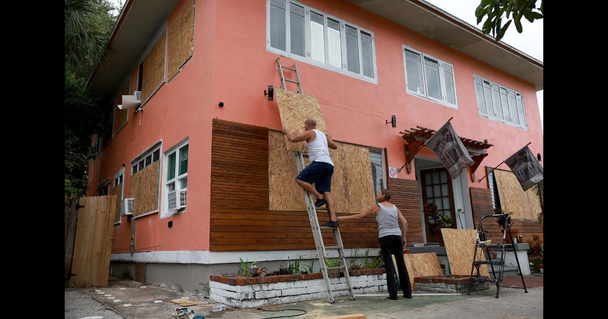 Edward Montgomery and Courtney Viezux board up Montgomery's apartment building as they prepare for the possible arrival of Hurricane Ian on September 27, 2022 in St Petersburg, Florida.