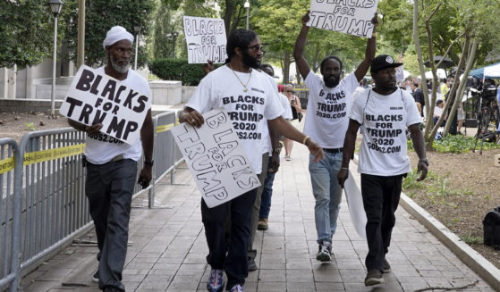 Black supporters of President-elect Donald Trump walk with signs and t-shirts promoting Trump in Washigton in 2023.