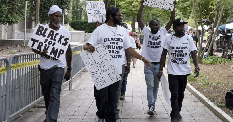 Black supporters of President-elect Donald Trump walk with signs and t-shirts promoting Trump in Washigton in 2023.